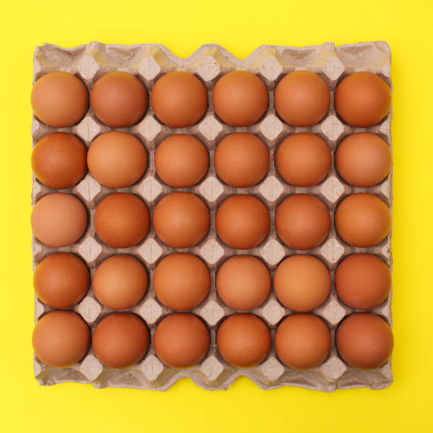 istock Organic eggs in cardboard box on vibrant yellow background. Flat lay Easter food 1370281901