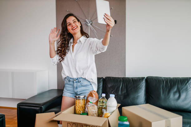 istock Young woman using digital tablet and packing donation box for poor 1370282162