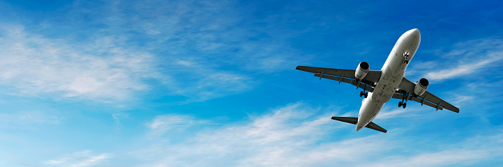 jet airplane landing in bright wispy sky, panoramic frame