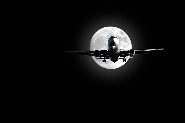 jet airplane landing at night with full moon