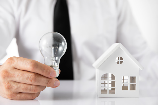 Mortgage concept with house model and businessman holding light bulb