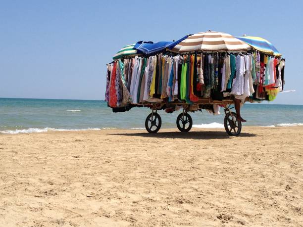 peddler on the beach, the cart is heavy and full of clothes