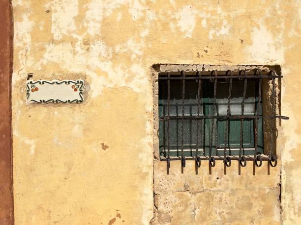 istock A small window with a bars and green shutters near a decorative sign 1370288328