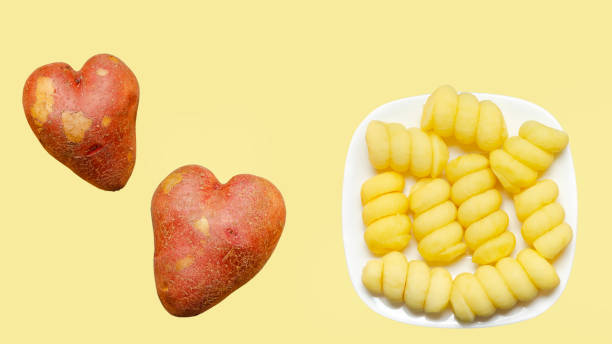 całe serce i surowe ziemniaki pokrojone w spirale na talerzu, przygotowane do smażenia. żółte tło, widok z góry - heart shape raw potato food individuality zdjęcia i obrazy z banku zdjęć