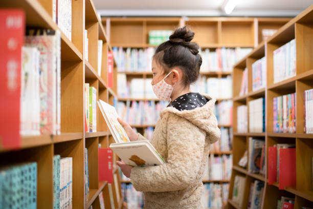 istock A girl wearing a mask chooses a book 1370292675