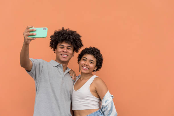 istock African American latin couple using smartphone in neutral background. 1370292833