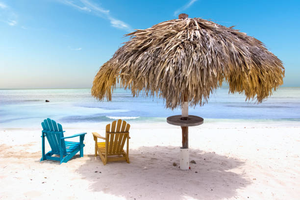 istock Straw parasol and colorful chairs on a tropical sandy beach 1370293909