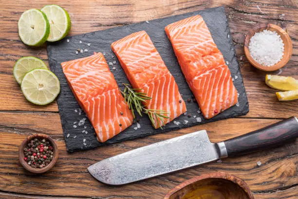 Photo of Fresh salmon fillets on black cutting board.