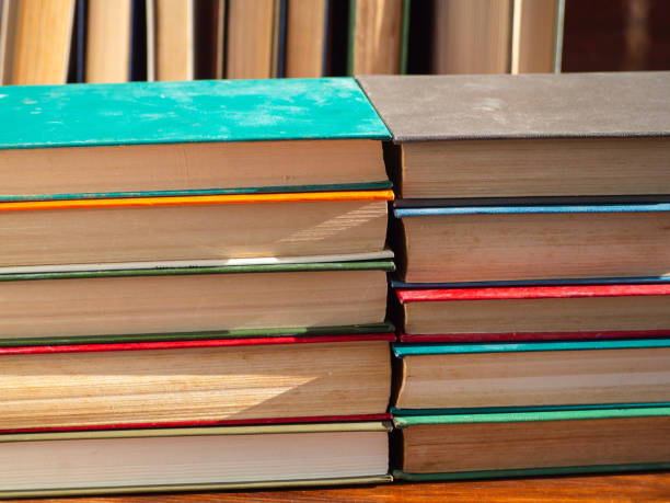 istock Stacks of old books with yellowed hardcover pages, illuminated by sunlight. Knowledge, science, desire to study, return to school. Colorful books on a wooden table. Self-education 1370299018