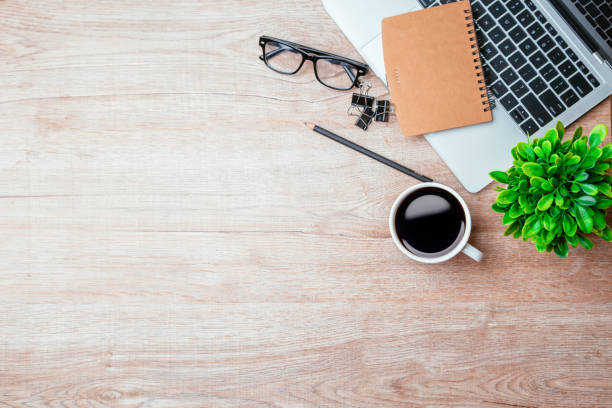 istock Work from home. desk office with laptop, blank notepad, coffee cup and pen on wood table. Flat lay top view copy spce. 1370303181