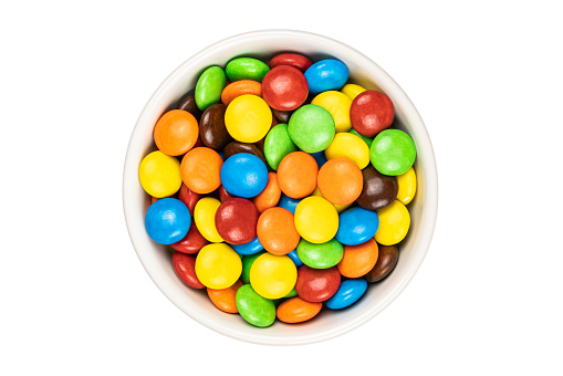 Top voew of multicolored chocolate button shape candy in white ceramic cup on white background with clipping path.
