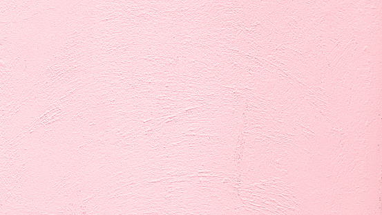 The weathered pink painted cement wall background shows signs of peeling, cracks, and dampness.