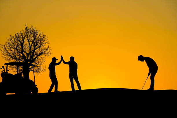 istock Two golfers rejoice after hitting the hole at sunset silhouetted. 1370306351