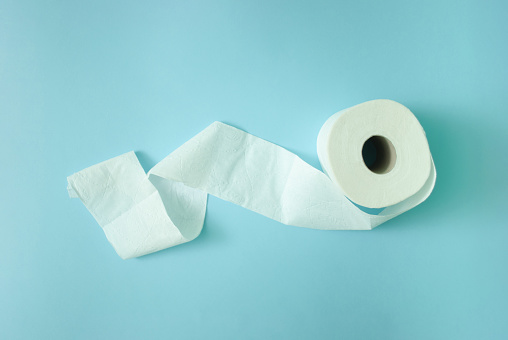 White toilet paper roll on light pastel blue background. Copy space, flat lay.