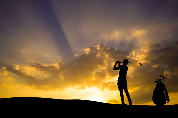 istock Golfers' hit golf ball toward the hole at sunset silhouetted 1370306510