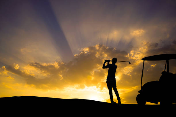 istock Golfers' hit golf ball toward the hole at sunset silhouetted 1370306511