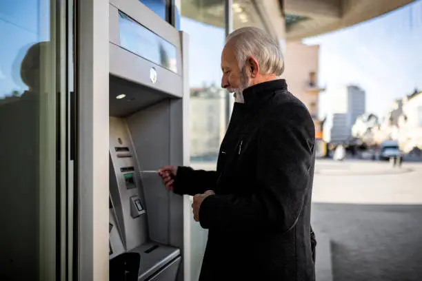 Senior businessman using Credit Card on ATM