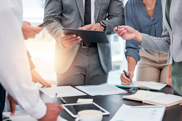 tiro de um grupo de empresários trabalhando em papelada e tecnologia durante uma reunião - business meeting - fotografias e filmes do acervo