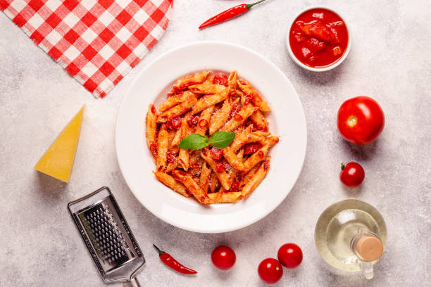 istock Classic italian pasta penne alla arrabiata with fresh basil on a light background, top view 1370309653