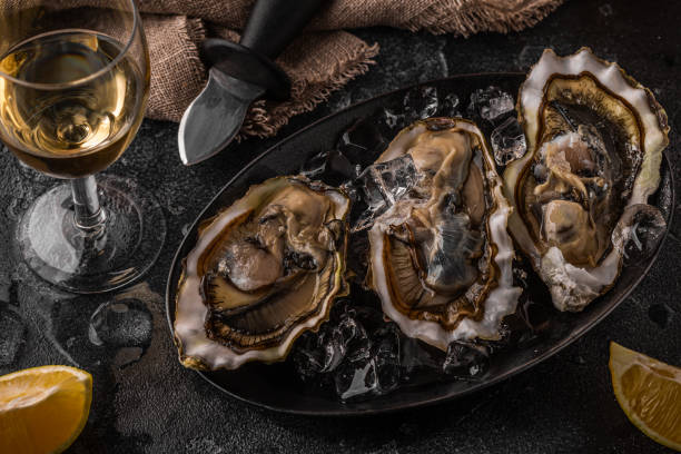 istock Fresh oysters close-up on ice served with lemon and wine. 1370310885