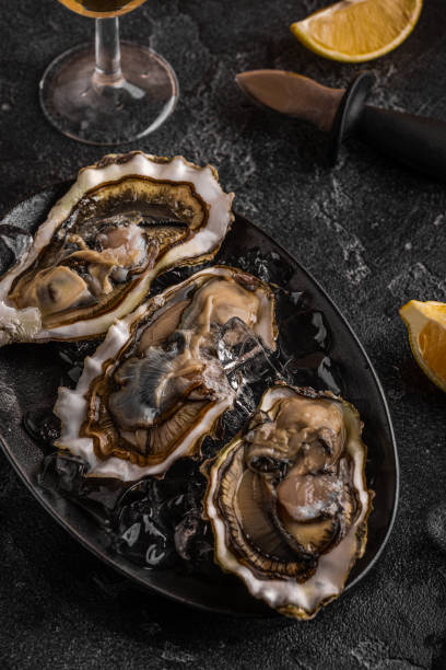 istock Fresh oysters close-up on ice served with lemon and wine. 1370311038