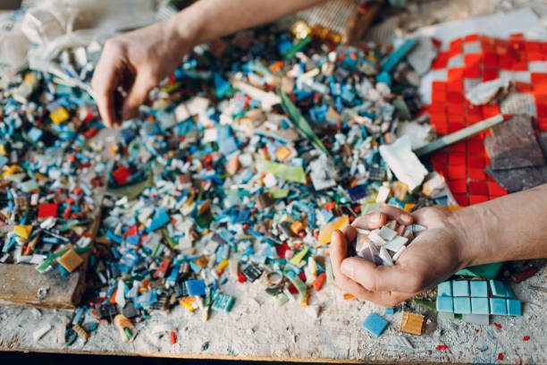 istock Man mosaics master chooses select smalt glass pieces for mosaic panel. Male mosaicist at work. 1370316928