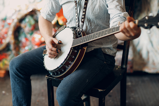 Músico masculino tocando la silla de banjo en el interior photo
