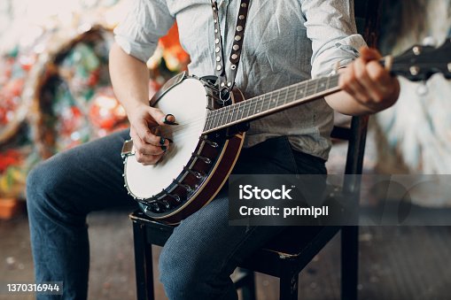 istock Male musician playing banjo sitting chair indoor 1370316944