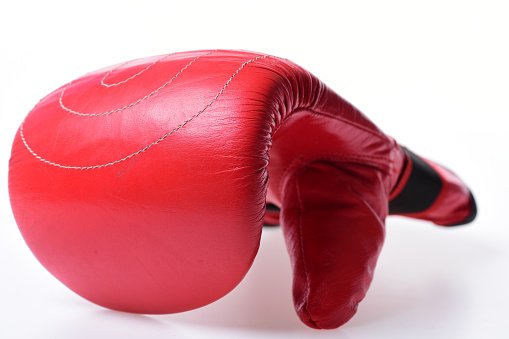 Protection and strength concept. Boxing glove in red color isolated on white background. Boxing gloves item lying in close up. Leather box equipment for fight and training.