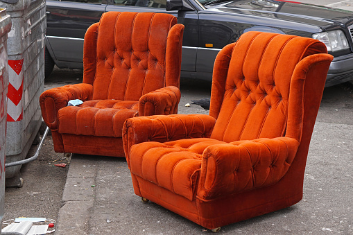 Two rejected plush orange armchairs furniture at street