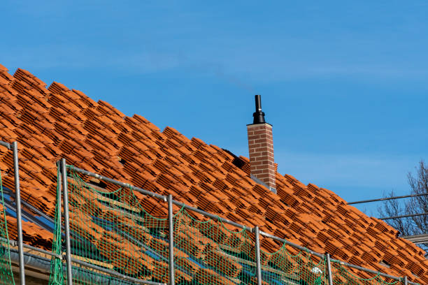 Stacks of red yellow ceramic roofing tiles for covering residential building roof under construction.