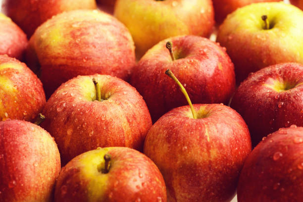 много красных яблок, свежие фрукты на рынке - wet apple стоковые фото и изображения