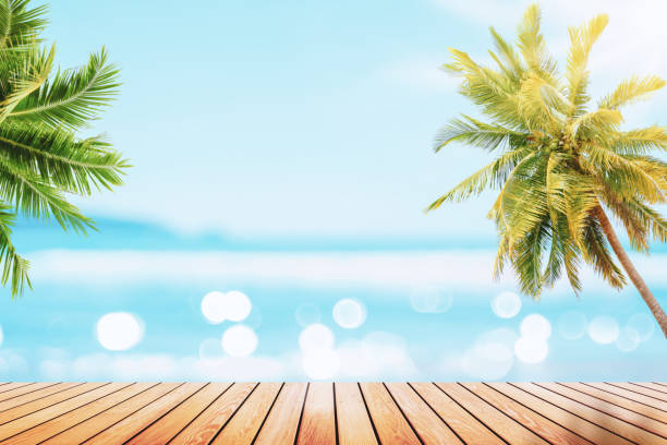 istock Blur tropical beach with bokeh sun light wave and palm tree on copy space empty old wood table abstract background. Product presentation in nature. 1370321139