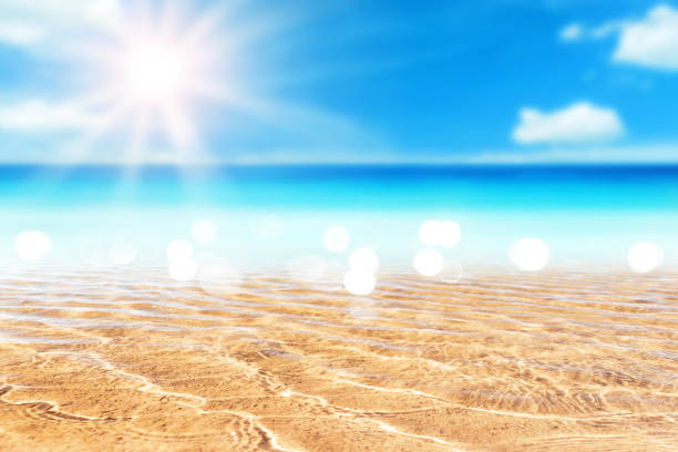 Copy space blur tropical beach with bokeh sun light wave on blue sky and white cloud abstract background. Summer vacation outdoor and travel holiday adventure concept. Vintage tone filter effect color.