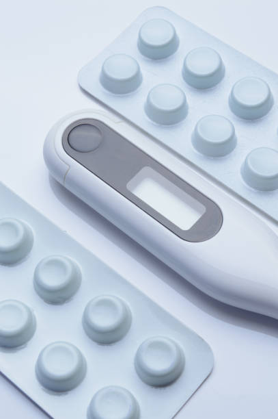 istock tablets in a package and a white electronic thermometer on a white surface close-up. 1370321814