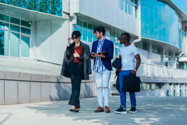 istock Businessman showing documents to his multi-ethnic co-workers in front of their big modern office building 1370324992