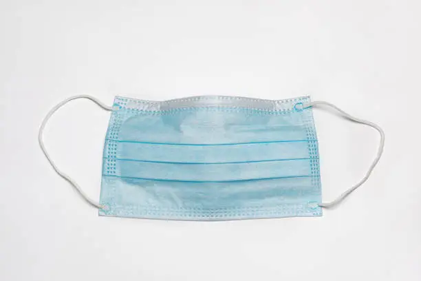 Photo of Surgical face mask isolated on white background. Covid-19 face covering mandate, requirement and health care concept.