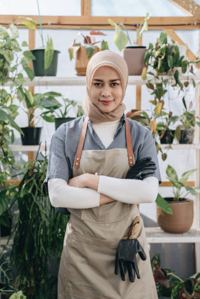 happy young woman gardening, watering plants in plant nursery at home. - growth tree spirituality tranquil scene imagens e fotografias de stock