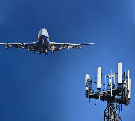 Mobile cell tower with 5G on C Band frequencies with airplane flying by. Illustration of Airlines worrying about interference with plane altimeter