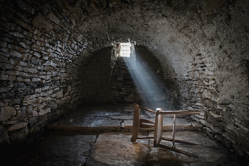 Scary underground, old dark cellar with an old abandoned chair