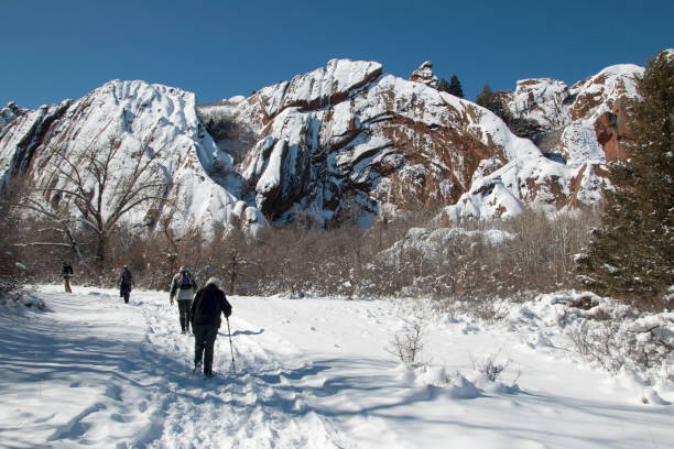 Senior adult winter hikers on the Fountain Valley Trail walk through the snowy red rock fountain formations of Roxborough State Park,  in Littleton, Colorado.
