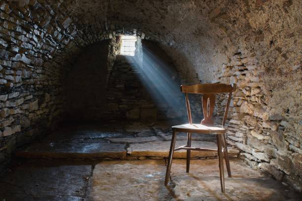 Scary underground, old dark cellar with an old abandoned chair Scary underground, old dark cellar with an old abandoned chair dungeon medieval prison prison cell stock pictures, royalty-free photos & images