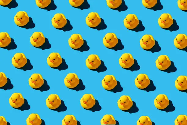 Photo of Yellow rubber duck toys pattern on seamless blue background.