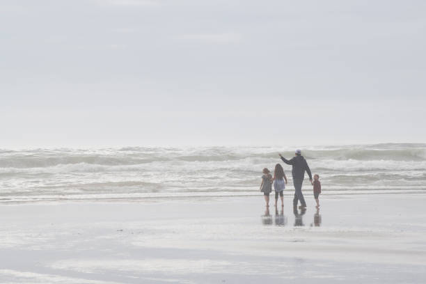 Cannon Beach, USA - September 5, 2021. A father with his three children walking on Cannon Beach, Oregon, USA