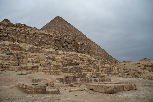 Ruins of the small pyramid of Queen Henutsen with Cheops Pyramid at background, Giza Plateau, Egypt. UNESCO World Heritage