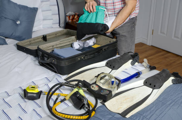 istock Man folding clothes in suitcase and scuba gear 1370330649