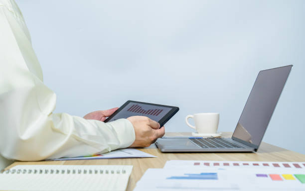 istock man work with tablet above laptop with copy space background 1370332423