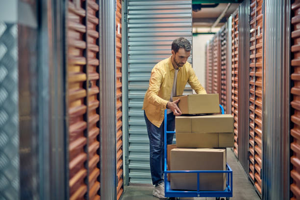 istock Focused order picker stacking cardboard boxes on the hand truck 1370336224