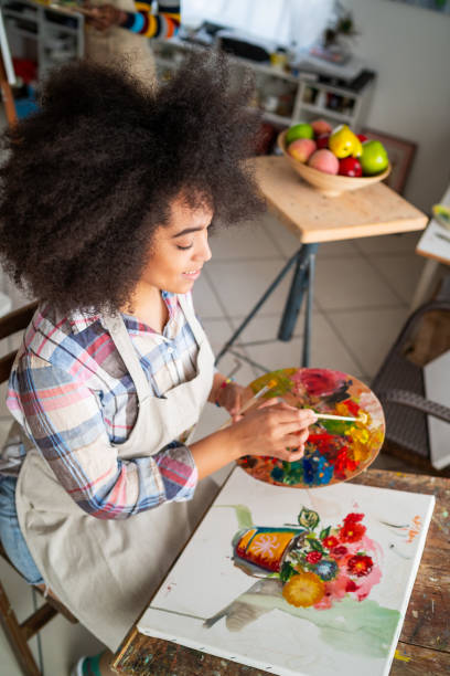 primer plano sobre la pintura de una artista afro femenina. artista fino sosteniendo paleta y un pincel y dibujando sobre un lienzo. - entertainment school art studio painter fotografías e imágenes de stock