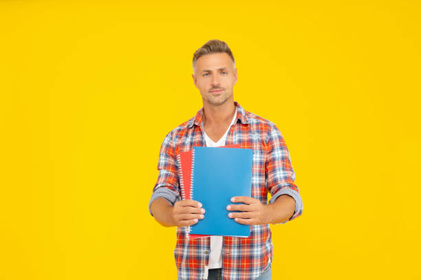 istock Serious university student holding books for education yellow background, copy space 1370336685